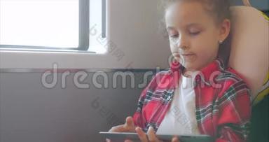 可爱的小女孩用平板娱乐。 儿童休闲时间，乘坐电动火车，玩手机游戏